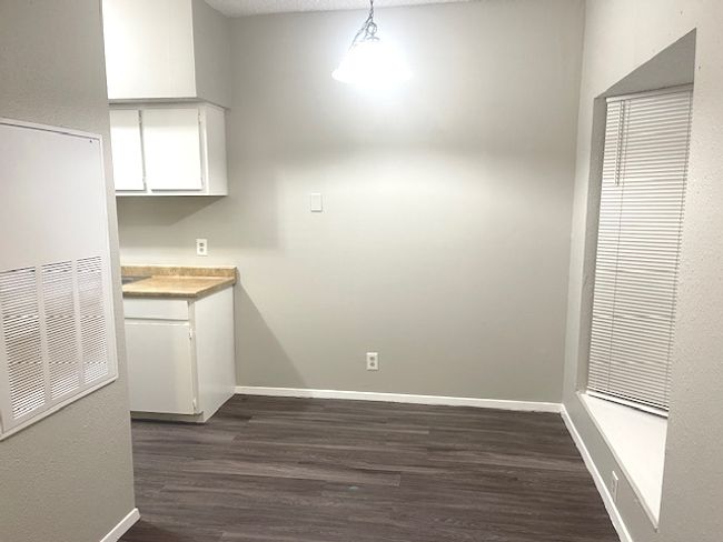Unfurnished dining area with dark wood-type flooring and baseboards | Image 5
