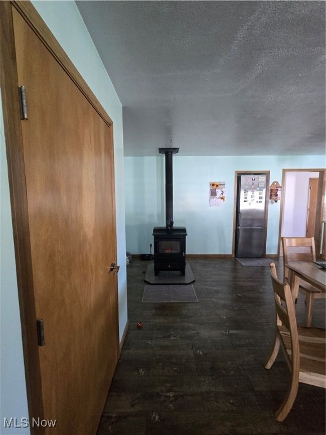 Living area with wood-type flooring, baseboards, a wood stove, and a textured ceiling | Image 34