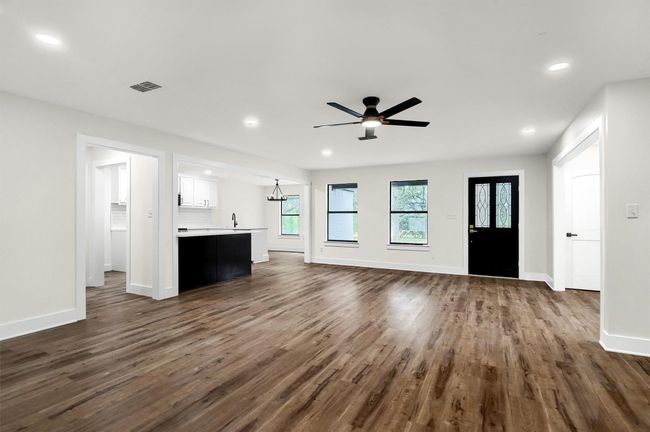 Unfurnished living room with dark wood finished floors, baseboards, recessed lighting, ceiling fan, and a sink | Image 5