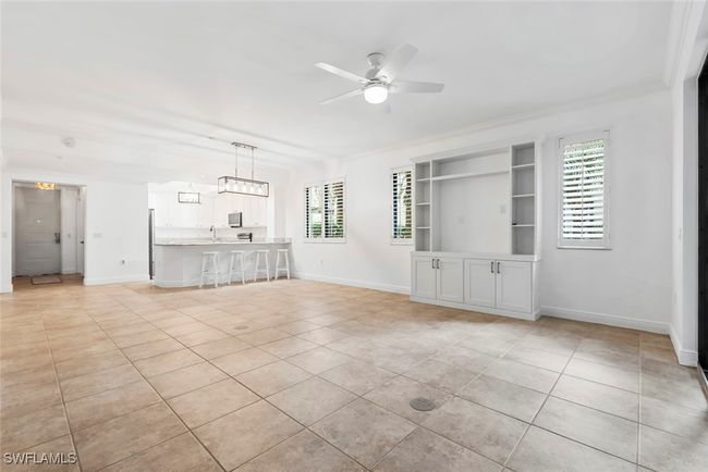 Unfurnished living room featuring ceiling fan, ornamental molding, light tile patterned flooring, built in shelves, and sink | Image 37
