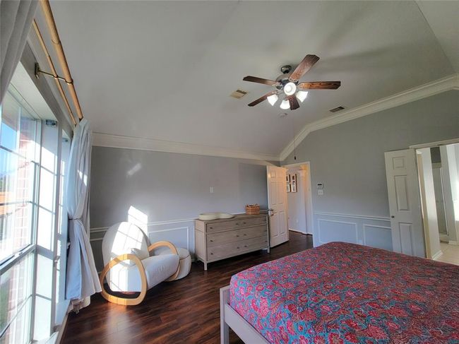 Bright and airy bedroom with large windows, hardwood floors, and a ceiling fan. Features a cozy reading nook and neutral decor for a modern feel. | Image 18