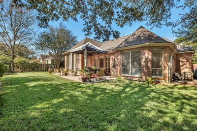 Here is a view of the rear of the house featuring a well-maintained lawn, a cozy outdoor seating area, and mature trees providing shade and privacy. | Image 2