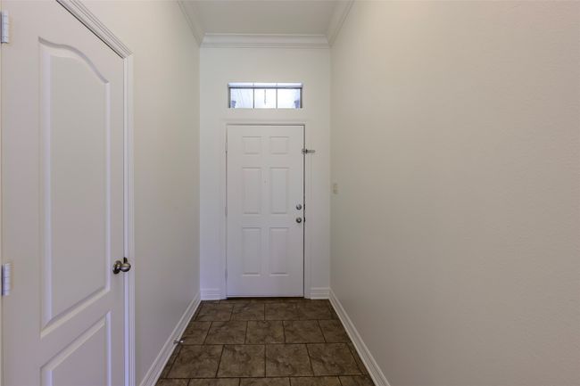 Doorway to outside featuring stone finish floor, crown molding, and baseboards | Image 7