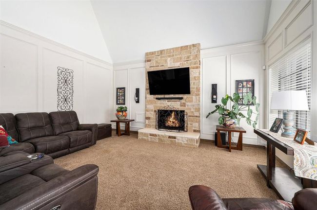 Comfortable family room offers a high ceiling, plush carpet, fireplace with stone surround and great backyard views. | Image 6