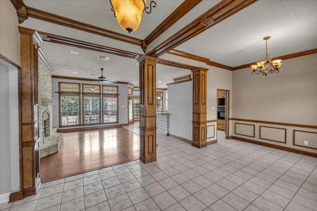 Empty room featuring ornate columns, crown molding, a chandelier, a ceiling fan, and light tile patterned floors | Image 16