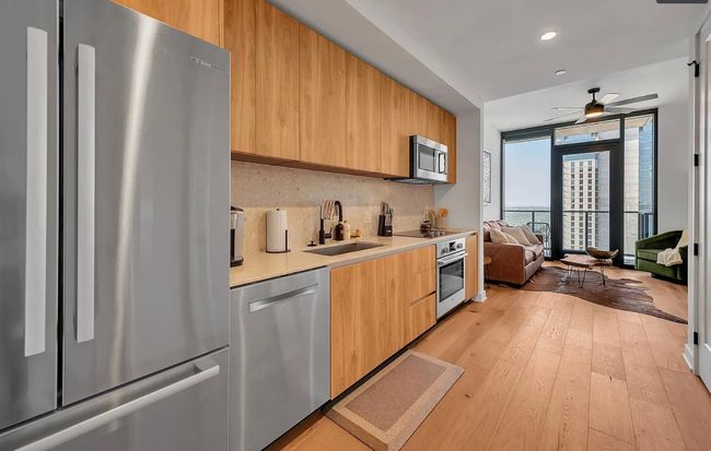 Kitchen with appliances with stainless steel finishes, modern cabinets, light countertops, a wall of windows, and a ceiling fan | Image 7