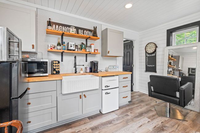 Kitchen with butcher block countertops, stainless steel microwave, a sink, light wood-style flooring, and freestanding refrigerator | Image 29
