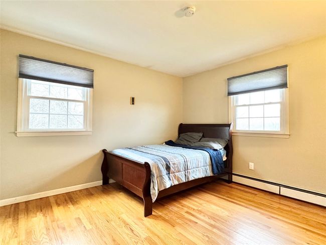 Bedroom with a baseboard heating unit, baseboards, and wood finished floors | Image 15