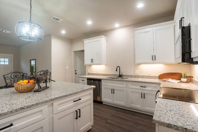 Kitchen featuring a sink, dishwasher, dark wood-type flooring, white cabinets, and pendant lighting | Image 11