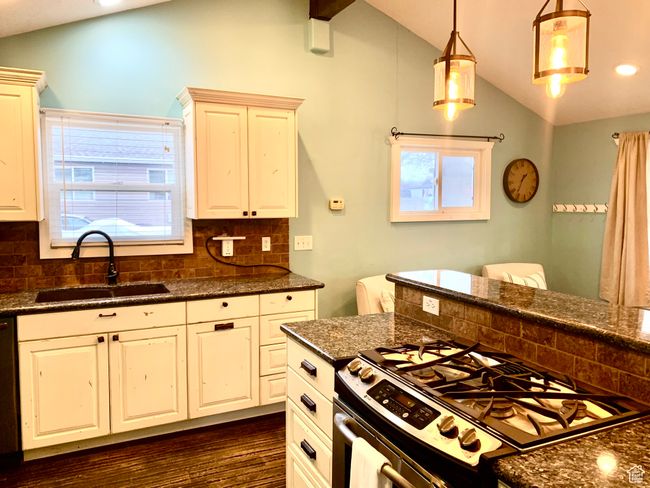 Kitchen featuring decorative backsplash, gas stove, decorative light fixtures, vaulted ceiling with beams, and sink | Image 7