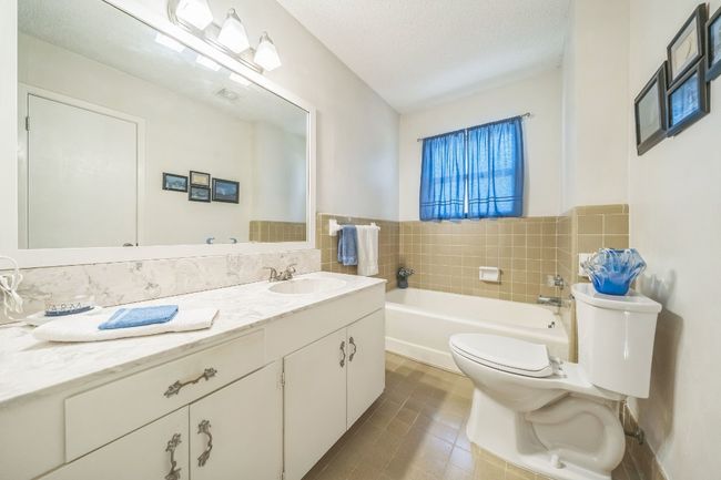 Hall Bathroom, bathtub only with vanity, tile patterned floors, toilet, a bath, and tile walls | Image 16