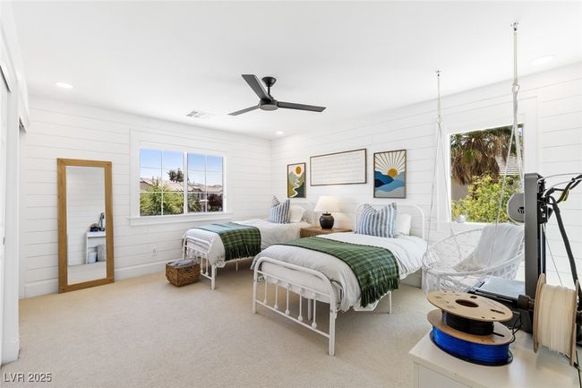 Carpeted bedroom with ceiling fan, wood walls, multiple windows, and visible vents | Image 32
