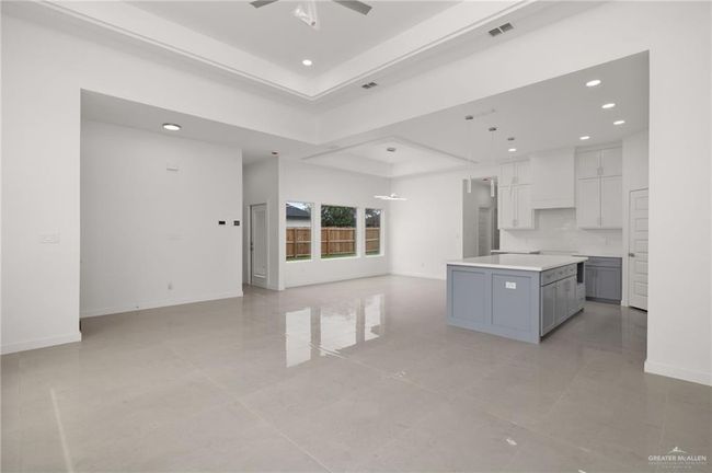 Kitchen featuring gray cabinetry, recessed lighting, open floor plan, a kitchen island, and a raised ceiling | Image 4