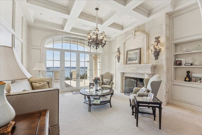 The formal living room with coffered ceiling and decorative stone fireplace offers lovely views. | Image 7