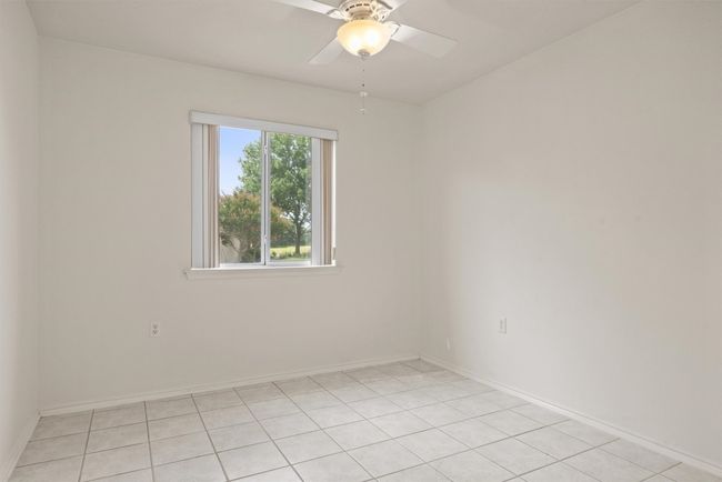 Empty room with ceiling fan and light tile patterned floors | Image 11