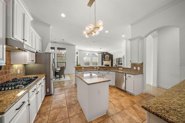 The kitchen combines style and functionality with granite countertops, stainless steel appliances, and expansive cabinetry. A central island enhances preparation space, while the breakfast bar offers casual dining. Its open layout seamlessly connects to the living area and naturally lit breakfast space, creating a welcoming atmosphere for culinary endeavors. | Image 19