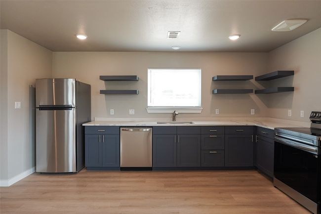 Kitchen featuring appliances with stainless steel finishes, open shelves, light wood-type flooring, and wall chimney exhaust hood | Image 6