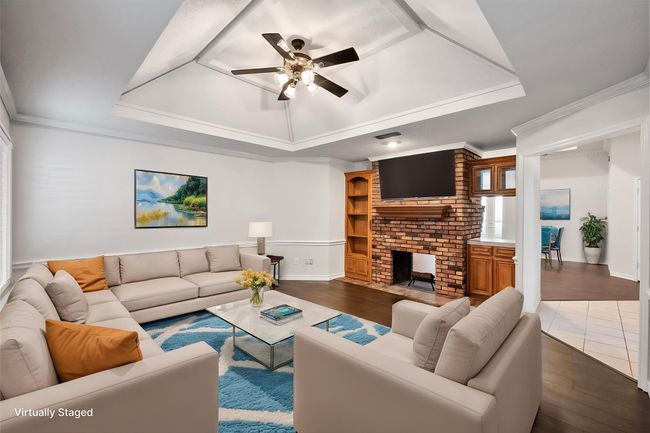The secondary living room is ideal as a gameroom, den or flex space. The inset vaulted ceilings have wood trim accents. The home was painted inside April 2025 to be fresh for the new owner. The creamy colors are highlighted with white trim making it open, light and bright. This room feautres handsome engineered wood floors. Perfect for those chilly spring nights, the beautiful brick wood burning fireplace is see thru to the other side. The built in shelving gives place to spotlight important trinkets. This room has a wall of windows for natural light and chair railing. | Image 4