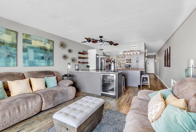 Living area with beverage cooler, visible vents, wood finished floors, and a textured ceiling | Image 25