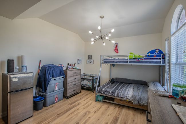 Bedroom with a chandelier, freestanding refrigerator, vaulted ceiling, and light wood finished floors | Image 16