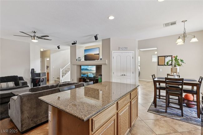 Kitchen featuring a kitchen island, stone countertops, hanging light fixtures, ceiling fan, and a chandelier | Image 31