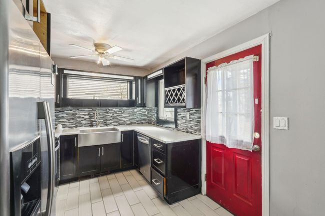 Kitchen with ceiling fan, appliances with stainless steel finishes, light countertops, a sink, and backsplash | Image 7