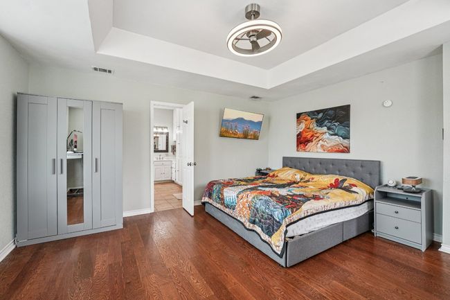 Bedroom with a raised ceiling, wood finished floors, and ensuite bathroom | Image 14