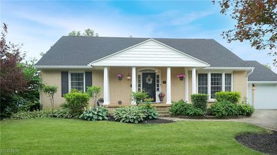 Bungalow featuring a garage, a front yard, and a porch | Image 1