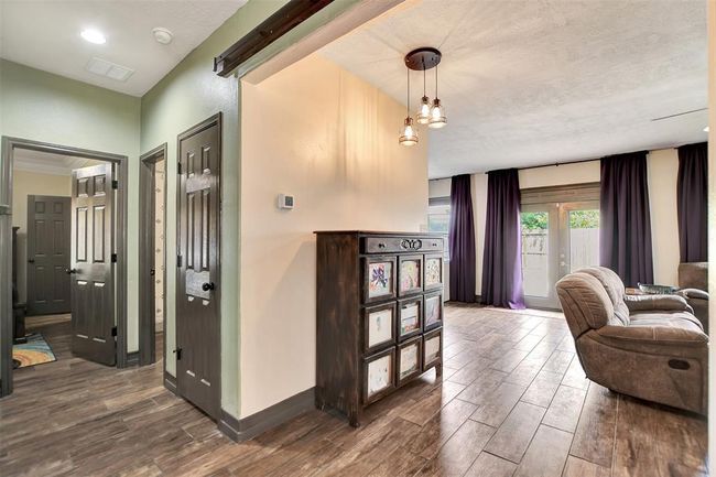 Experience seamless flow from the dining area: the hallway leads to the guest bedroom and utility room on the left, while the kitchen and family room open up on the right. | Image 10