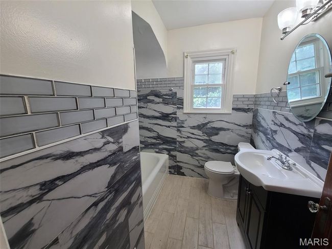 Bathroom featuring tile walls, vanity, wainscoting, a bath, and wood finished floors | Image 21