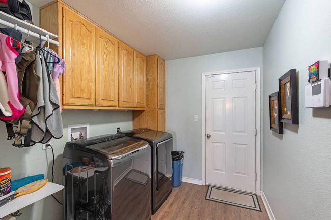 Laundry room with light wood-style flooring, baseboards, washer and clothes dryer, and cabinet space | Image 22