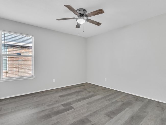 Empty room with wood finished floors, a ceiling fan, and baseboards | Image 13