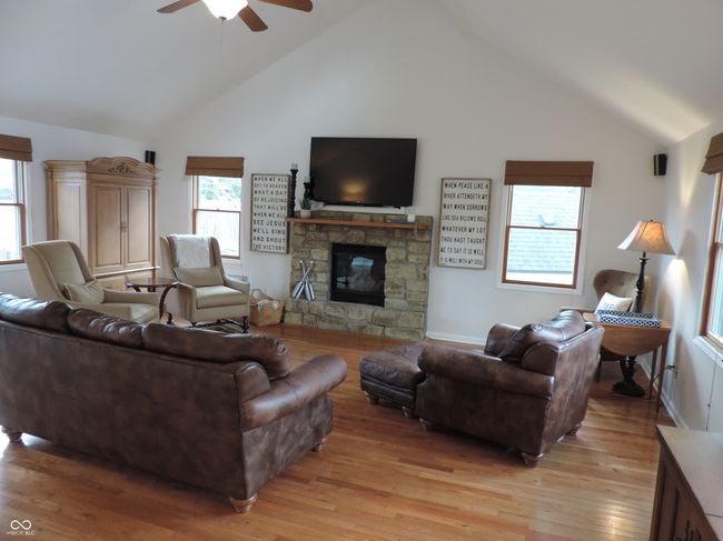 living area with a high vaulted ceiling, a fireplace, and light wood-type flooring | Image 9