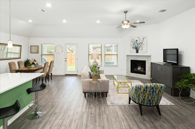 Living area featuring visible vents, a tiled fireplace, lofted ceiling, recessed lighting, and wood finished floors | Image 8