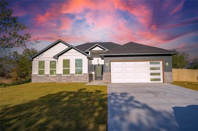 View of front facade featuring a lawn and a garage | Image 1