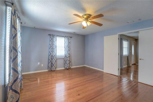 Spare room featuring a wealth of natural light, visible vents, a ceiling fan, and wood finished floors | Image 30