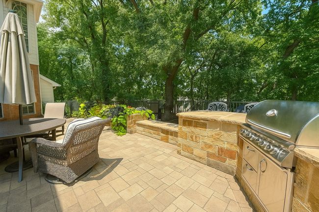 Fenced backyard with a patio area, outdoor dining area, and view of scattered trees | Image 16