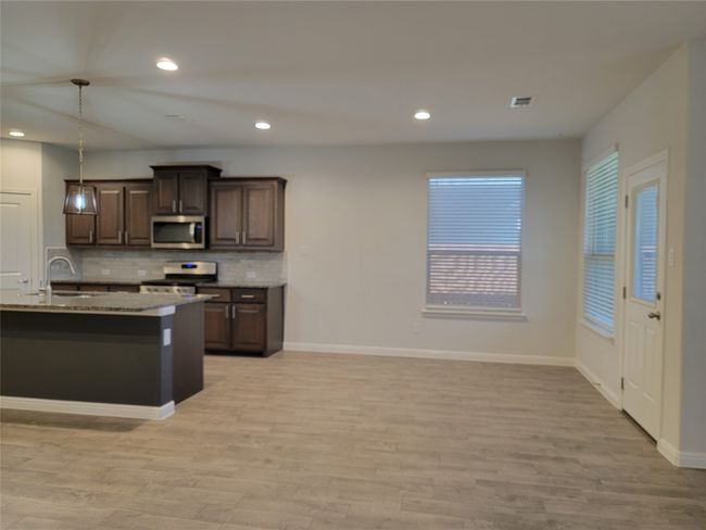 Kitchen featuring appliances with stainless steel finishes, light wood-type flooring, decorative backsplash, a sink, and recessed lighting | Image 12