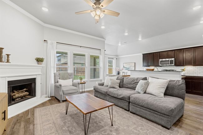 Living room featuring recessed lighting, ornamental molding, a ceiling fan, wood like tile flooring, and a fireplace with raised hearth | Image 23