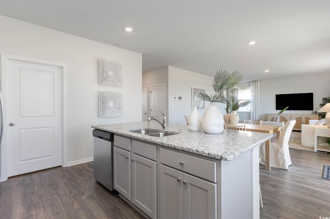 Kitchen with gray cabinets, dark wood-style flooring, stainless steel dishwasher, a sink, and light stone counters | Image 7