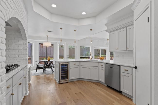 Kitchen featuring appliances with stainless steel finishes, beverage cooler, a peninsula, light countertops, and recessed lighting | Image 9