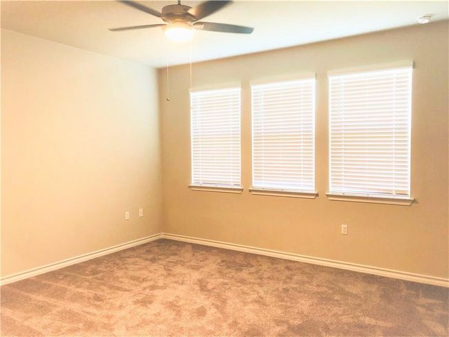 Empty room with carpet floors, ceiling fan, and a smoke detector | Image 13