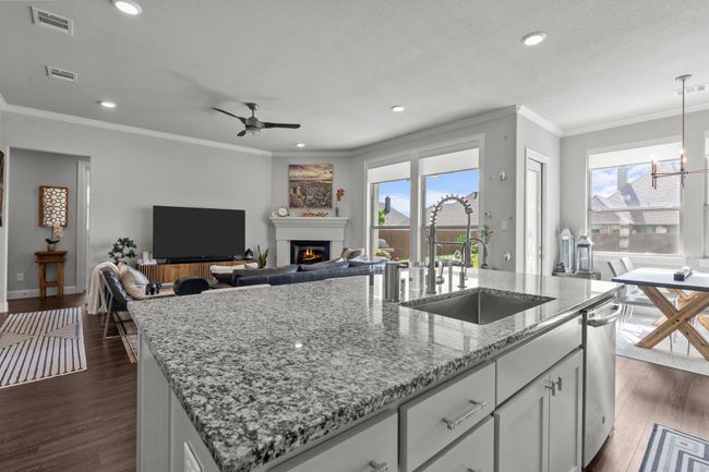 Kitchen featuring a center island with sink, a ceiling fan, plenty of natural light, a glass covered fireplace, and recessed lighting | Image 7