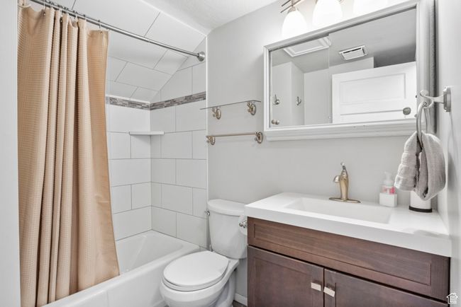 Bathroom featuring shower / tub combo, vanity, toilet, visible vents, and lofted ceiling | Image 11