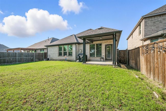 Back of property with brick siding, a patio area, a fenced backyard, and a shingled roof | Image 31