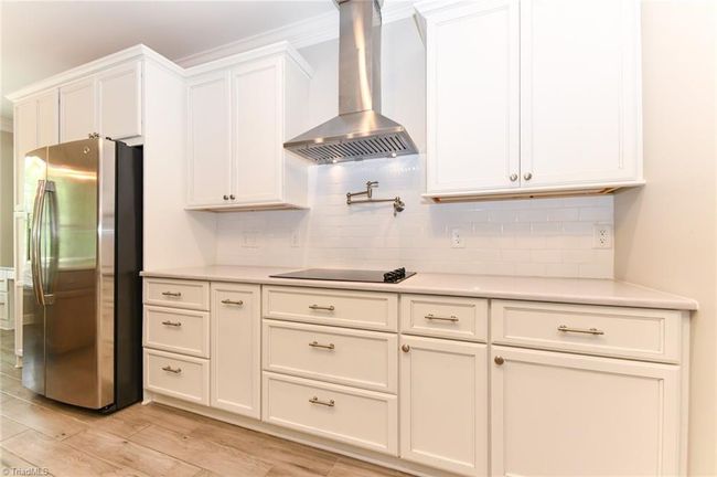 Modern cooking area with pot filler and stainless vent hood | Image 8
