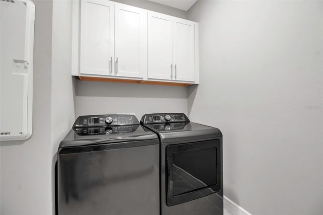 Laundry has upper cabinets over the washer and dryer | Image 55