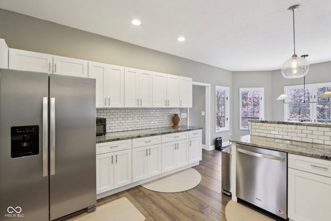 kitchen featuring white cabinetry, tasteful backsplash, stainless steel appliances, dark stone counters, and dark wood-style floors | Image 15