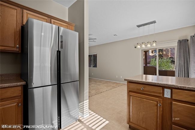 Kitchen with baseboards, decorative light fixtures, brown cabinetry, light tile patterned floors, and freestanding refrigerator | Image 13