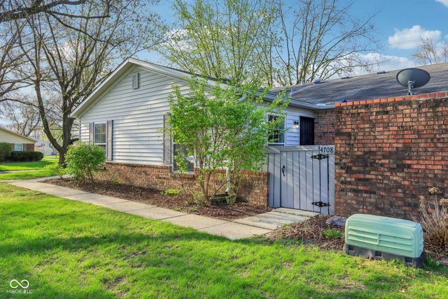 view of side of property featuring a gate, a yard, and brick siding | Image 23